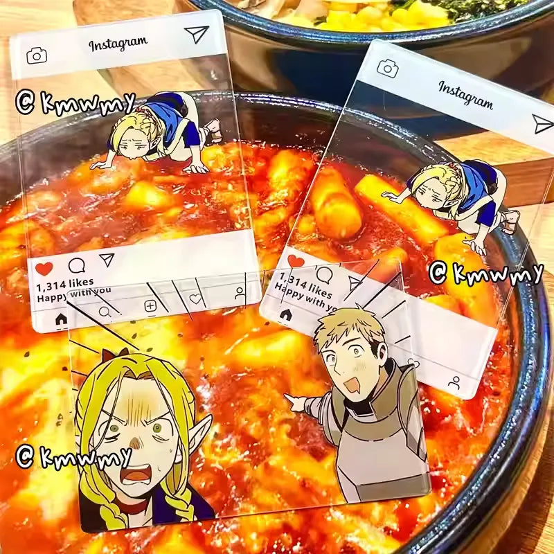 An acrylic transparent card featuring Delicious in Dungeon (Dungeon Meshi) characters Marcille and Laios in a playful food-themed scene. Marcille is wide-eyed with shock, while Laios grins excitedly, pointing to the center of the image with drool dripping from his mouth—as if spotting an irresistible meal. The card is propped against a backdrop of delicious real-world dish (e.g., a juicy steak or steaming stew), blending the anime’s fantasy hunger with mouthwatering reality. The translucent acrylic gives 