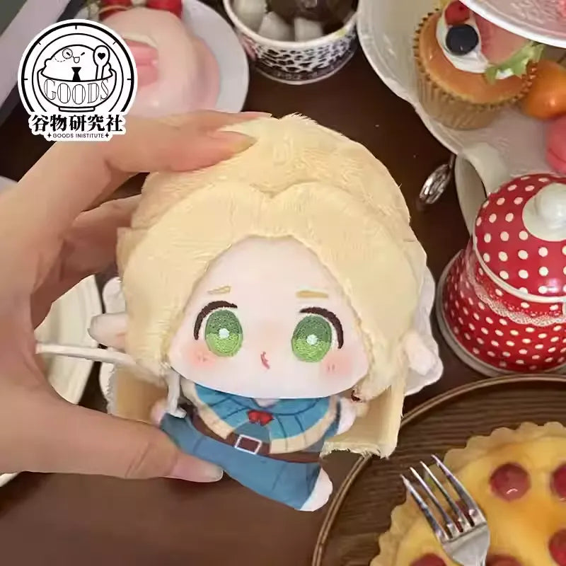 A soft, mini plush keychain of Marcille from Delicious in Dungeon (Dungeon Meshi), featuring her round, pouty ‘bun face’ with flushed cheeks, big sparkling eyes, and blonde hair styled in loose waves. Her pointy elf ears peek out cutely, and the squishy fabric makes her extra huggable—perfect for attaching to bags or keys!